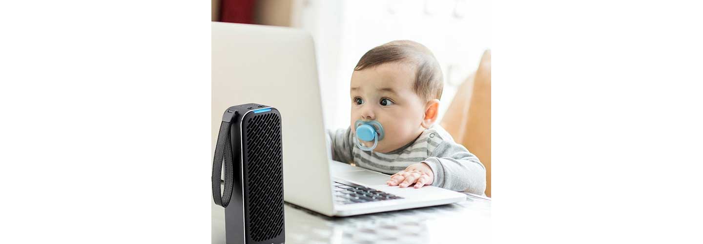 An adorable baby stares at a laptop monitor as the LG PuriCare Mini Air Purifier works in the foreground.