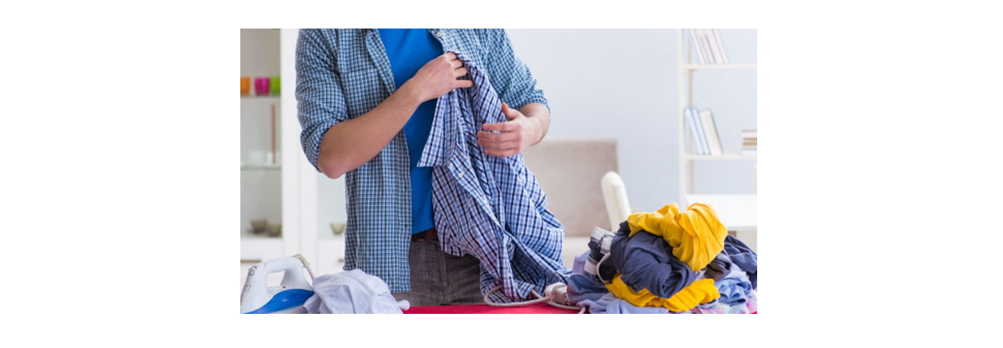 A man prepares to iron out the wrinkles in his clothes