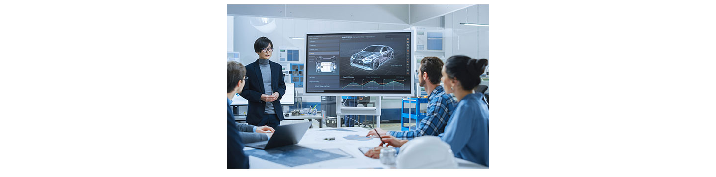 A team having a meeting at the office with a picture of an automobile displayed on a screen