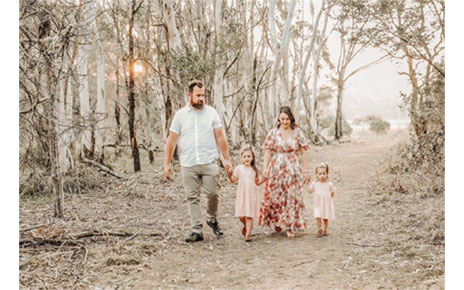  A family of four walking hand-in-hand through an Australian forest that has been ravaged by one of last year’s bush fires.
