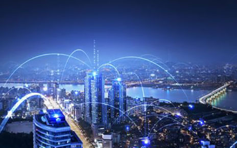 A city skyline at night with buildings connected with blue light to depict telecommunication technology.