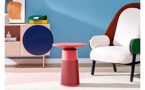 A lifestyle image of LG PuriCare Aero Furniture in Crème Rose against a modern, color-popping living room backdrop. 