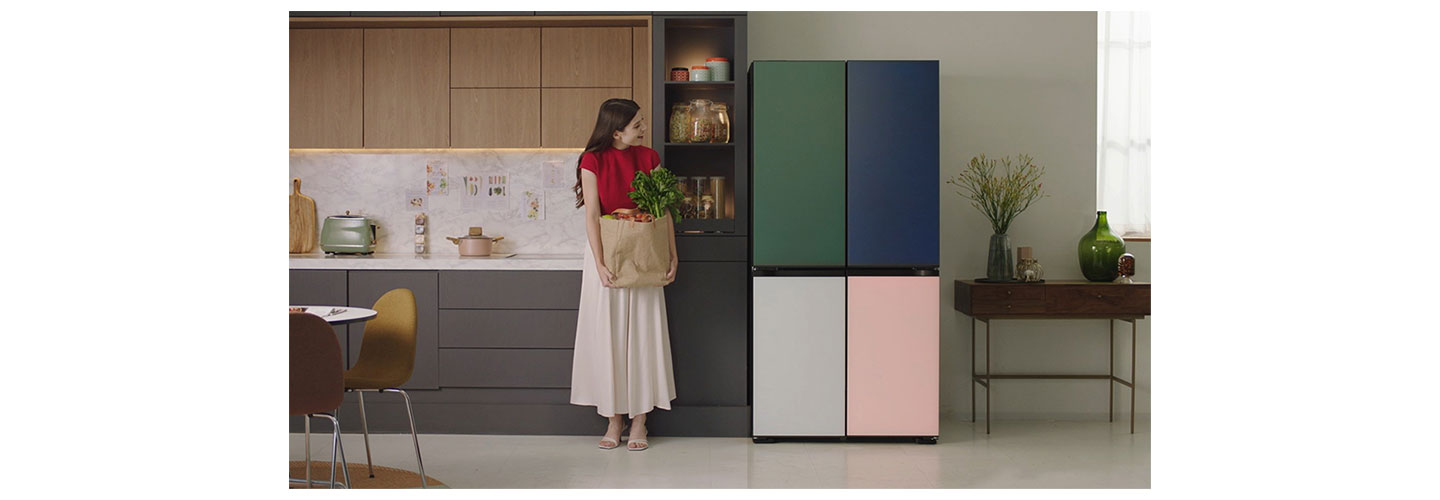 A woman holding a bag of groceries is standing next to LG MoodUP InstaView™ refrigerator