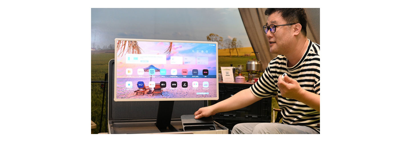An LG representative showing connectivity ports at the bottom of the LG StanbyME Go model in landscape mode