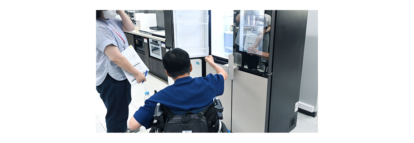 A man is testing the Easy Handle Kit applied to the LG InstaView refrigerator doors, and a woman is standing on the left