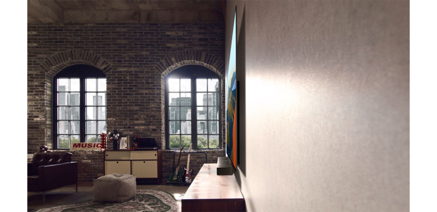 A side view of LG OLED M3 hanging on a living room wall as sunlight pours in from its large windows