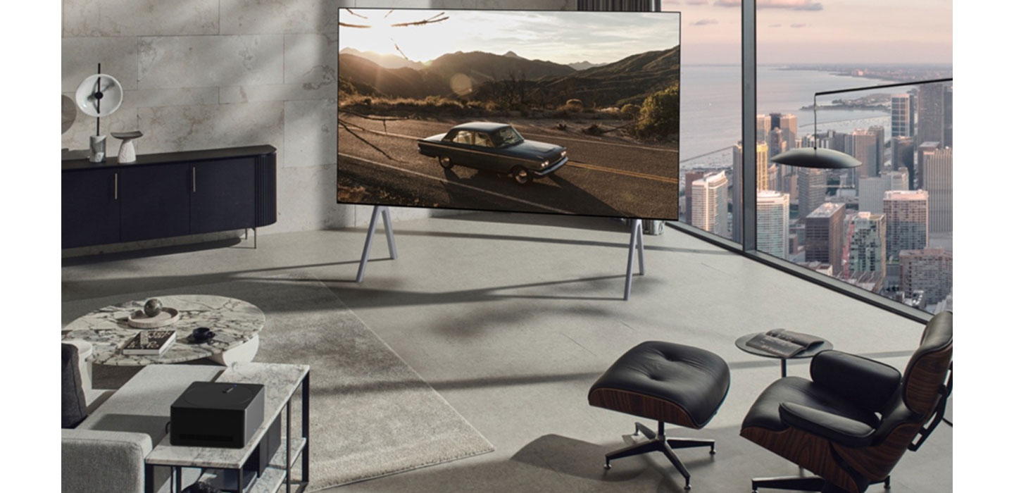 LG OLED M3 displaying a car riding on a country road inside a modern living room of a high-rise apartment
