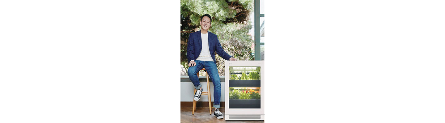 Shin Sang-youn, head of Sprout Company sitting on a chair next to LG tiiun and placing his hand on the product