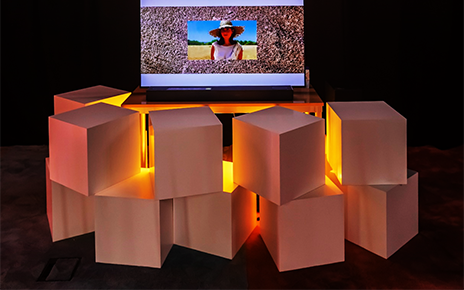 “Terraferma” by María Leyba and Mikaela Martínez displayed on LG OLED TV with decorative cubes and neon lighting surrounding the exhibit