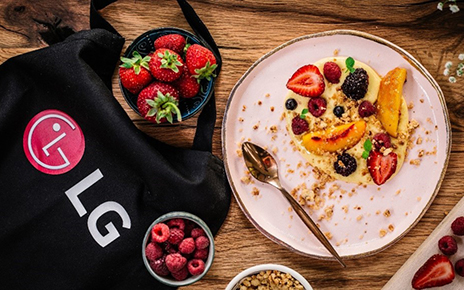 A promotional image showing an LG bag surrounded by plates and bowls of healthy natural foods including strawberries and raspberries.