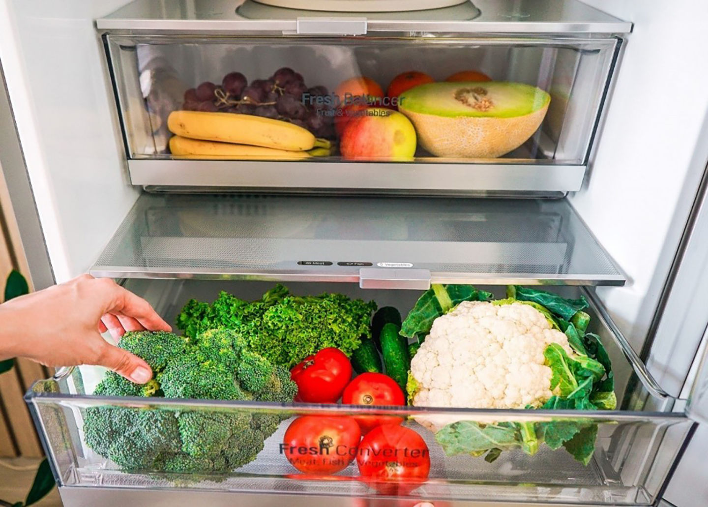 A close-up of LG V+ refrigerator’s innovative Fresh Balancer drawer on top of an opened Fresh Converter drawer, the former holding fruits and the latter storing vegetables.