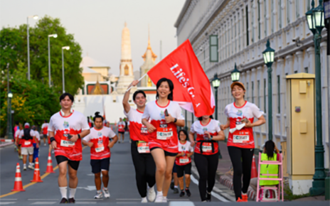 A photo of people running in a 10K Race holding and waving Life's Good banner