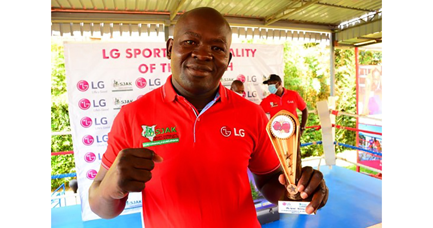 A photo of boxer Elly Ajowi making a proud fighting pose while holding his LG trophy