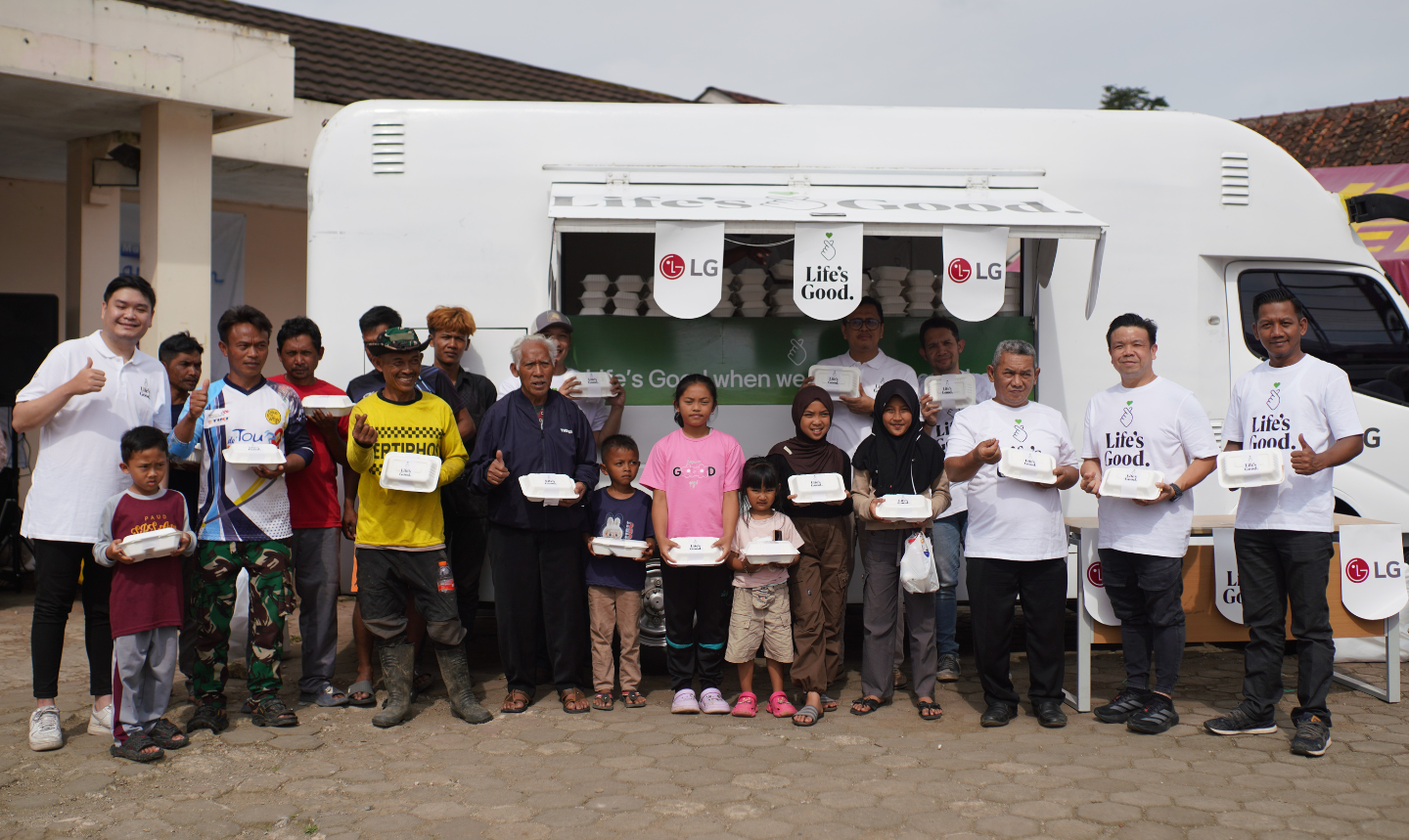 A group of people smile while holding boxed meals in front of a food truck.