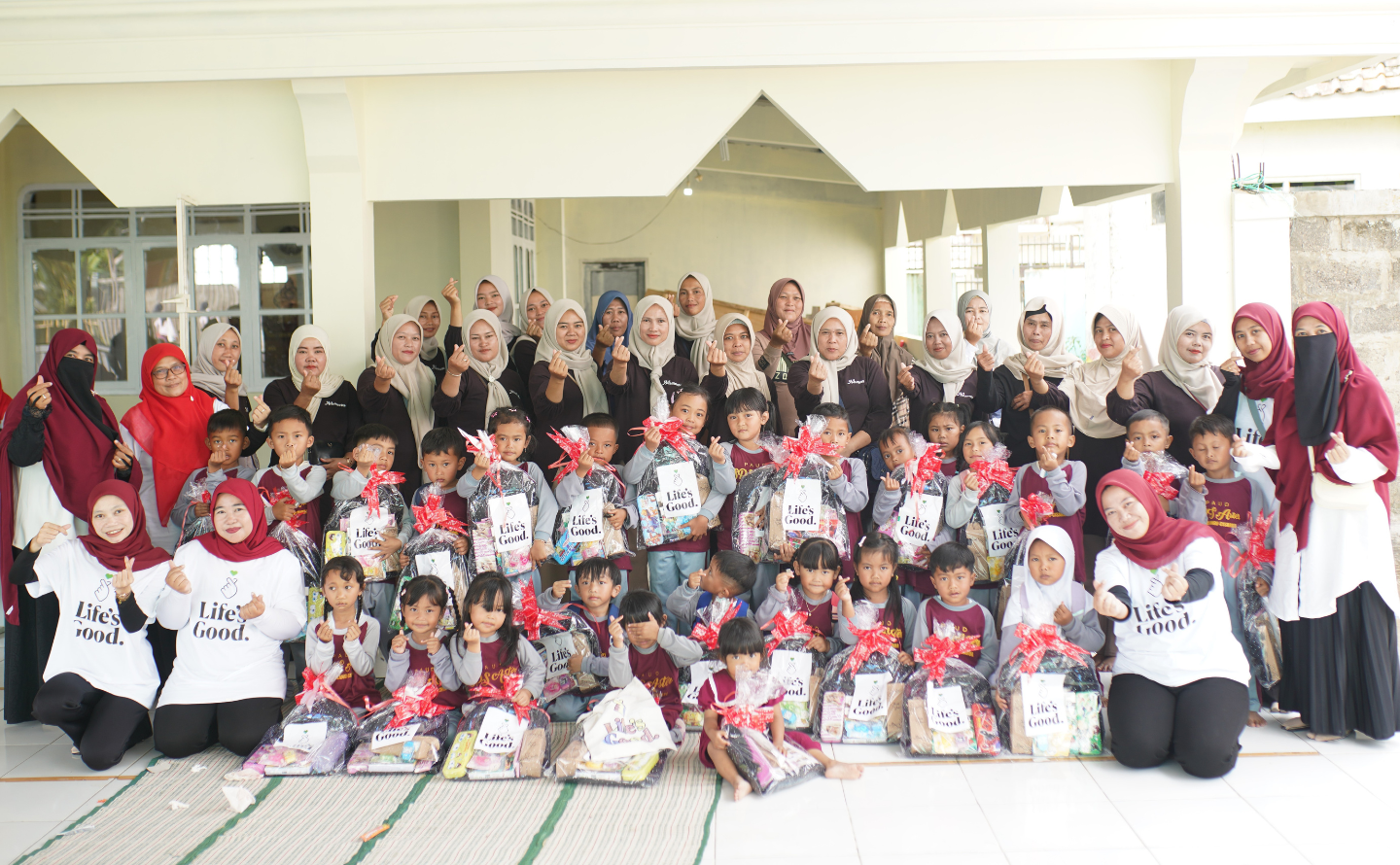 A large group of children hold gifts from LG Indonesia representatives. 