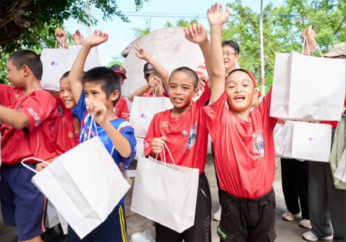 A picture of a group of children from the school holding gift bags from LG