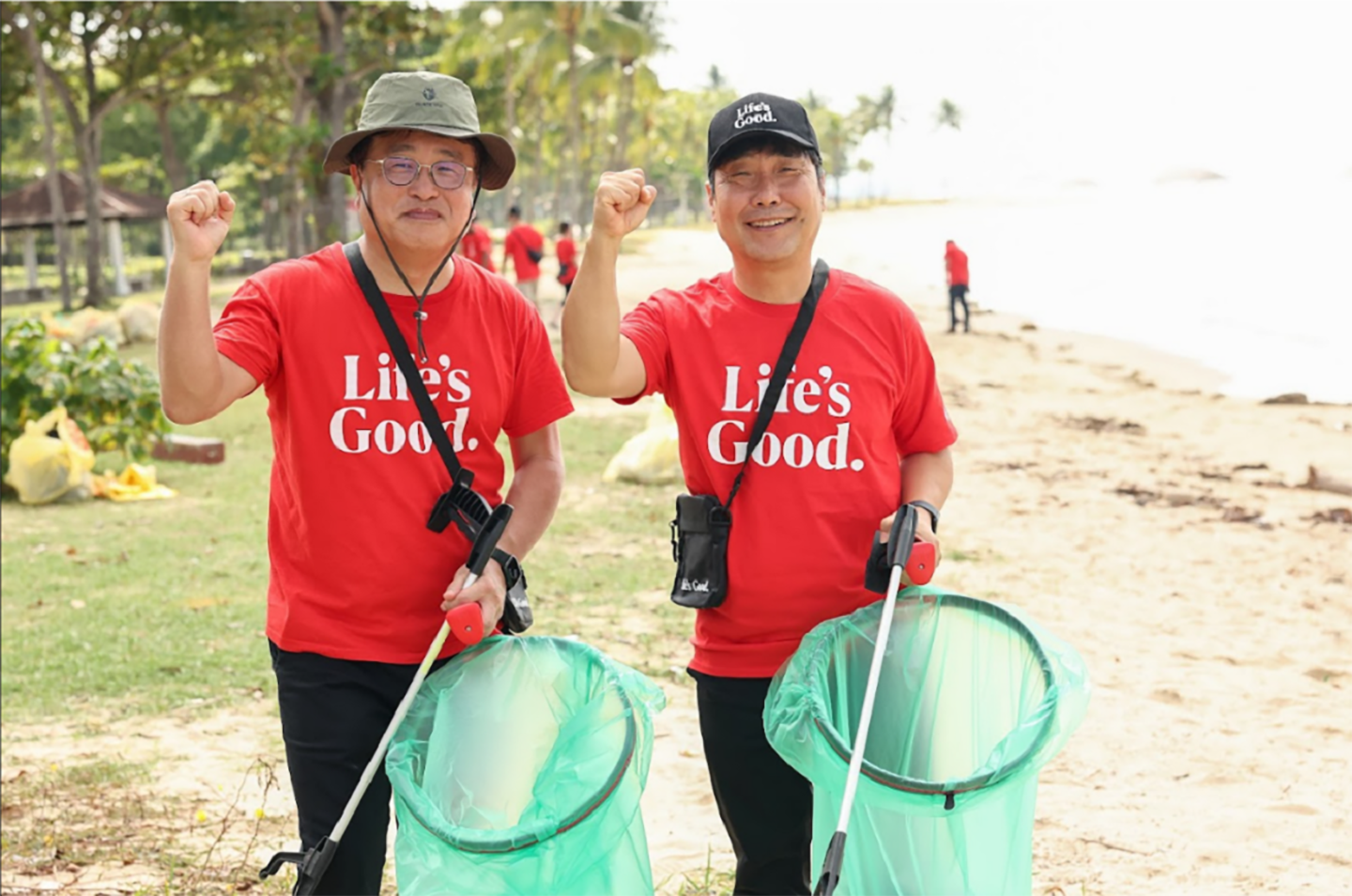 A picture of LG Singapore employees posing for a picture with their fists up at the ocean