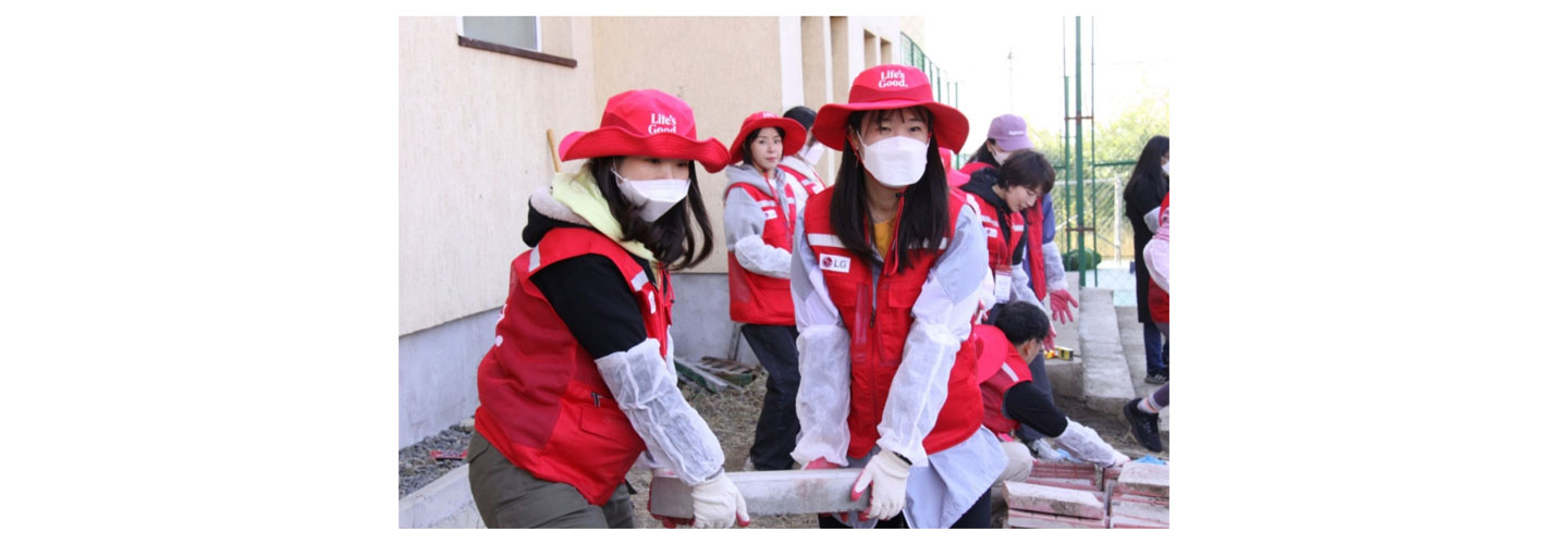 Two Life's Good volunteers moving a heavy brick together
