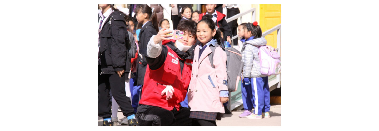 A Life's Good volunteer taking a photo with a young girl