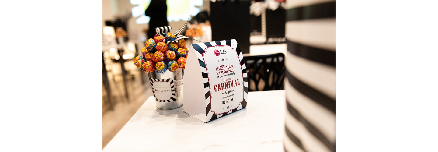 A sign for the LG gram Carnival stands on a table next to an LG-branded pot filled with lollipops