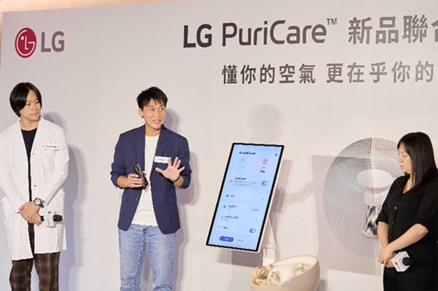 Three speakers are presenting the LG PuriCare AeroCatTower while standing beside a vertical screen during the Cat Living Showcase.