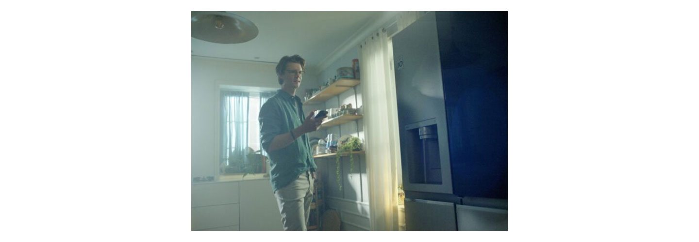 A man interacting with the LG refrigerator via smartphone