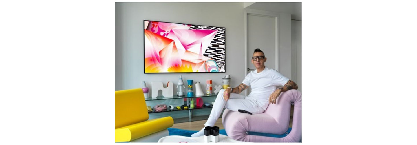 Karim Rashid sits next to the LG GALLERY DESIGN TV which is displaying his painting, DREAMSKAPE