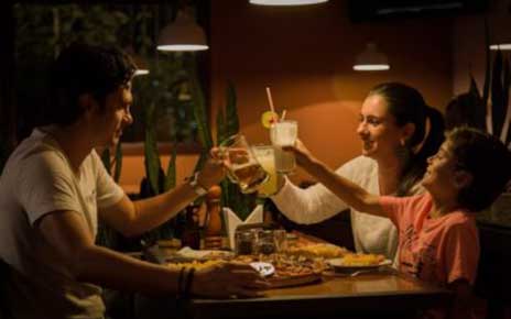 A family ‘cheers’ as they eat around the dinner table under dim lighting