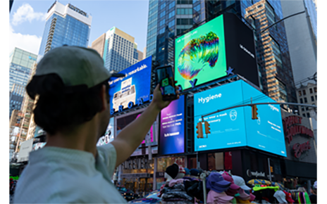 A passerby taking a picture of LG's massive, high-definition digital billboard in Time Square, New York displaying the artwork of David McLeod