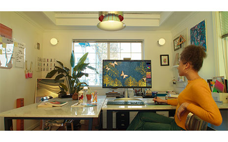 A woman is editing an image using LG UltraFine monitor and a mousepad