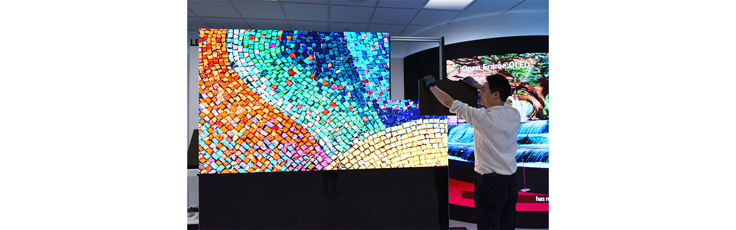 A man demonstrating how easy LG LED SIGNAGE is to install as he fits one of the final LED panels to complete a colorful display