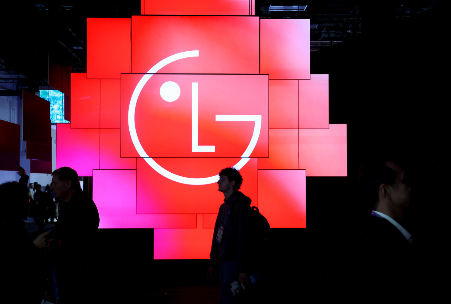 The 38 LG OLED evo W6 screens of the In Tune Monument display an illuminated LG logo, with silhouettes of visitors passing through the dark space.