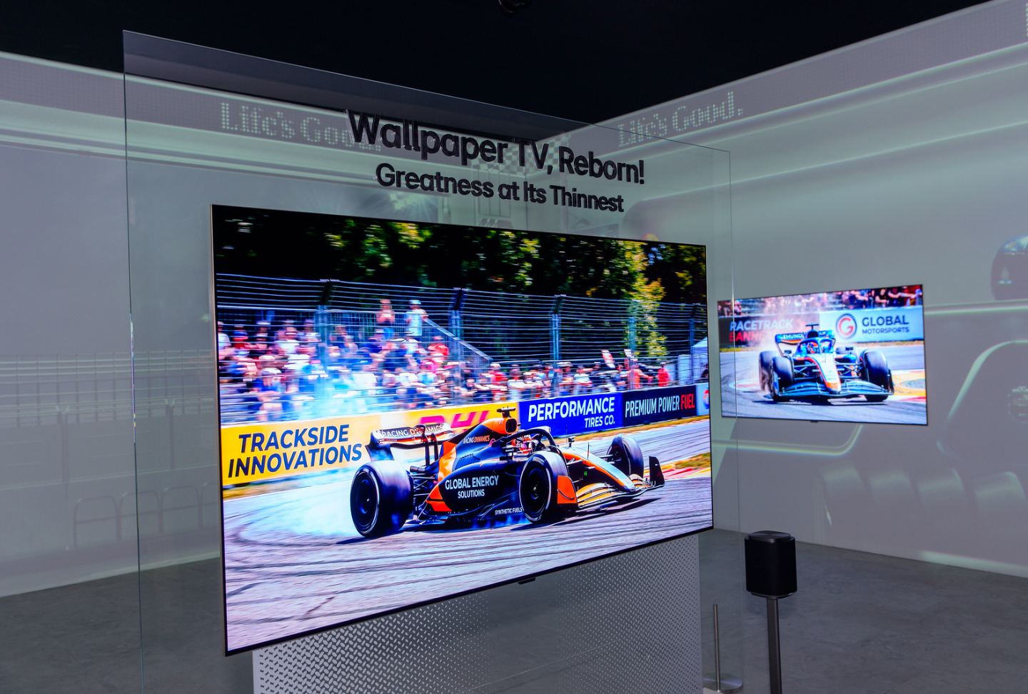An LG Wallpaper TV is attached to a transparent stand in the middle of the Viewing in Tune zone, displaying a dynamic car racing scene on the screen.