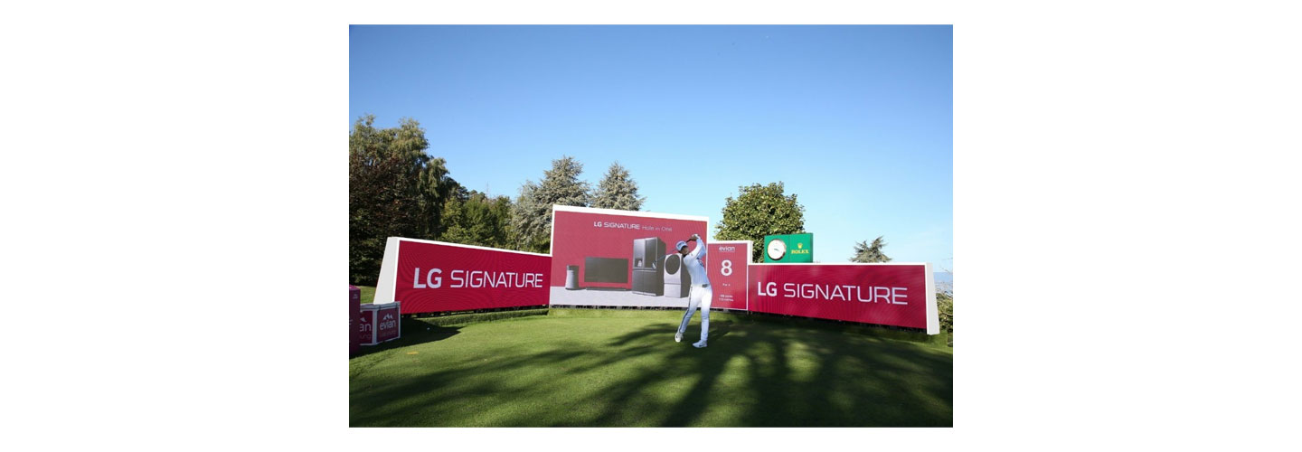 A golfer hits a ball right in front of the LG Signature signage.