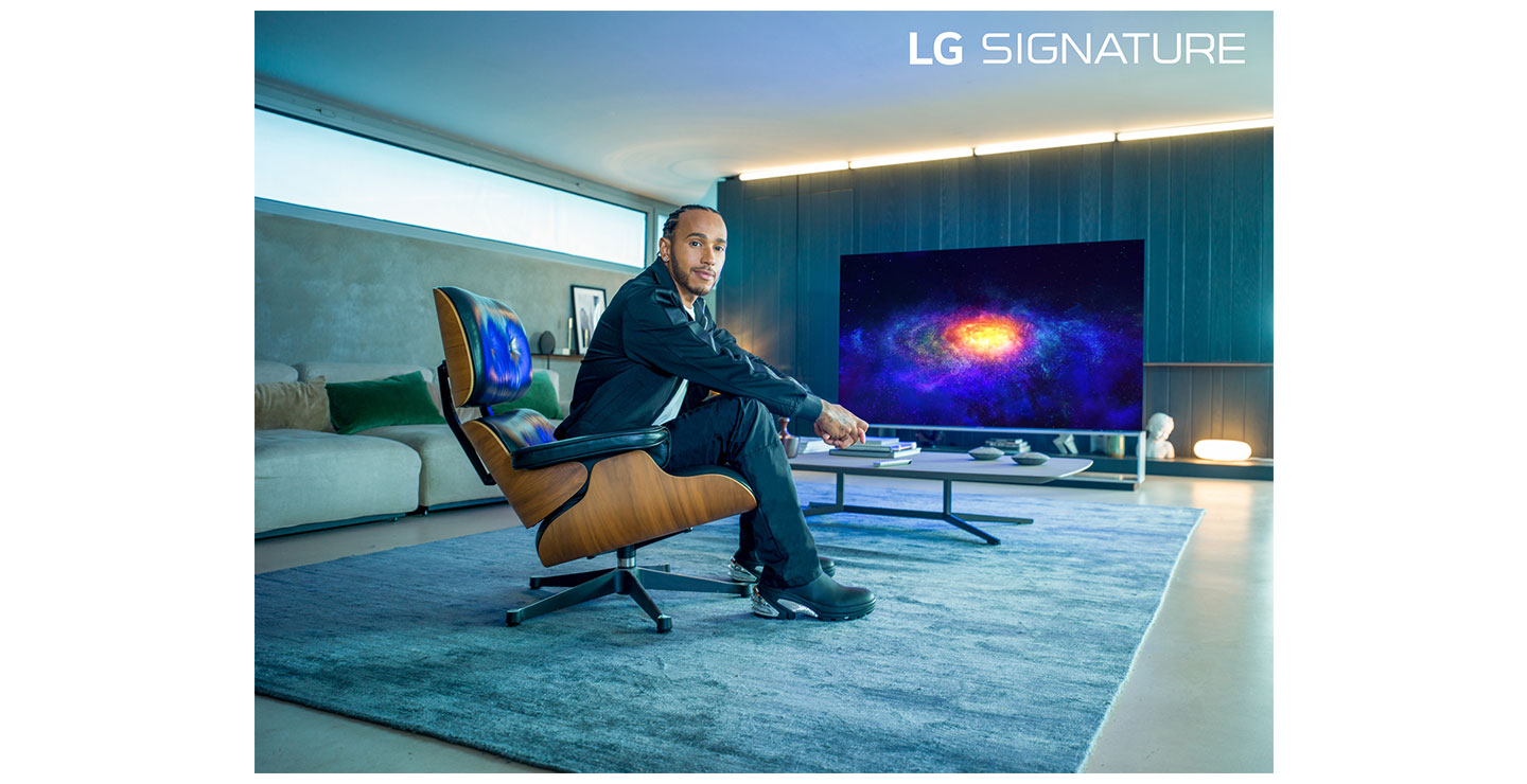 World Champion Lewis Hamilton, who has been appointed as a global ambassador for LG SIGNATURE, sitting in front of LG OLED TV as he poses for the camera