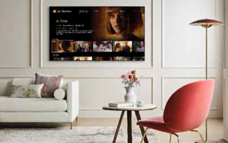 A wall-mounted LG TV in a modern living room displaying LG Channels with the movie 'In Time' on its Watch Now page