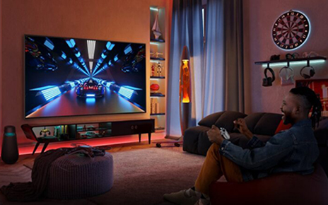 A gamer playing a racing game in a dimly lit living room via cloud gaming