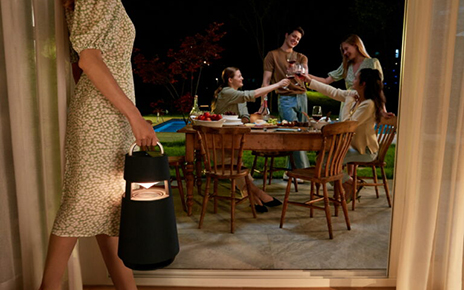 A woman carrying LG XBOOM 360 into the backyard for a party held during the night
