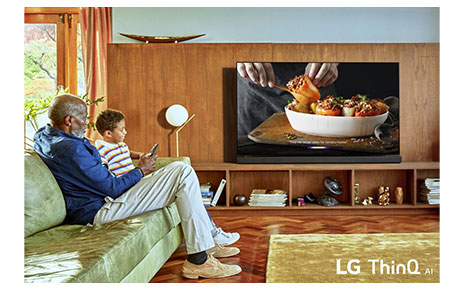 A granddad and grandson watch their LG OLED TV with LG ThinQ AI in their home