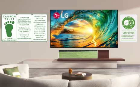 A wall-mounted LG TV displays a vibrant sunset alongside graphics of recognized sustainability certifications.