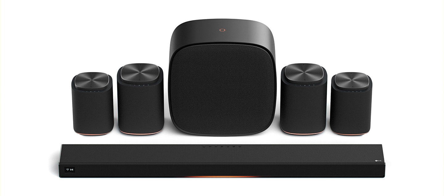 The LG Sound Suite features a sleek soundbar, four cylindrical satellite speakers and a rounded square subwoofer, set against a white background.