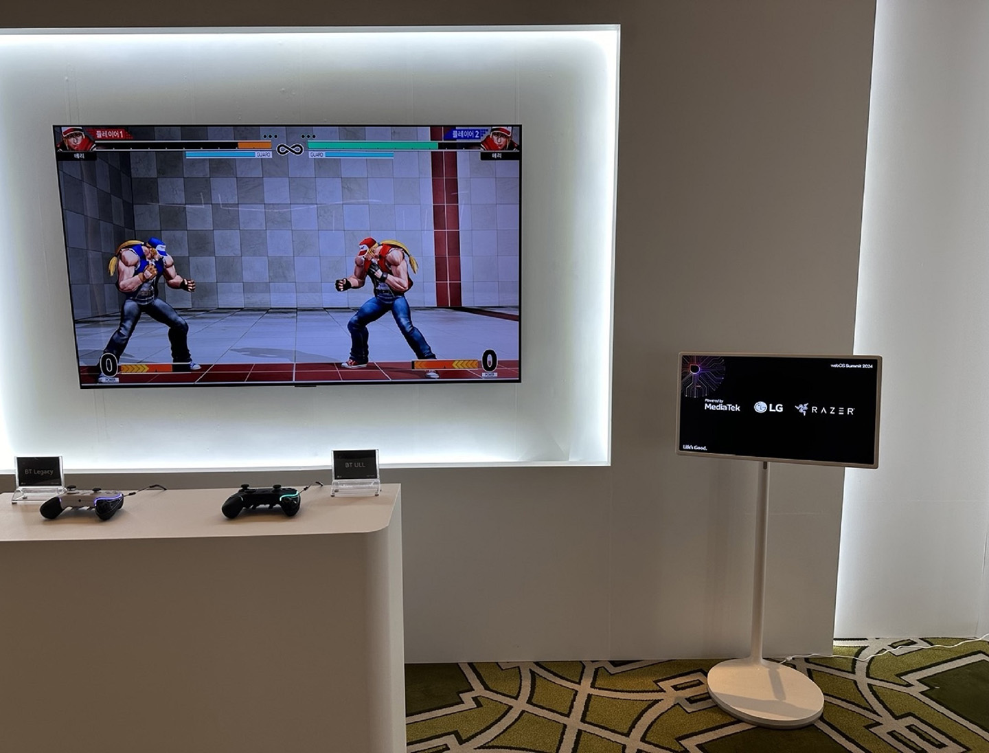 An LG monitor stands next to the wall-mounted screen and table of controllers, showcasing the collaboration between LG, MediaTek and Razer