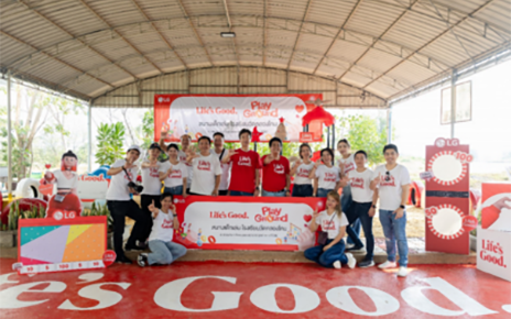 A picture of a group of people gathered around at the venue holding LG logo signs