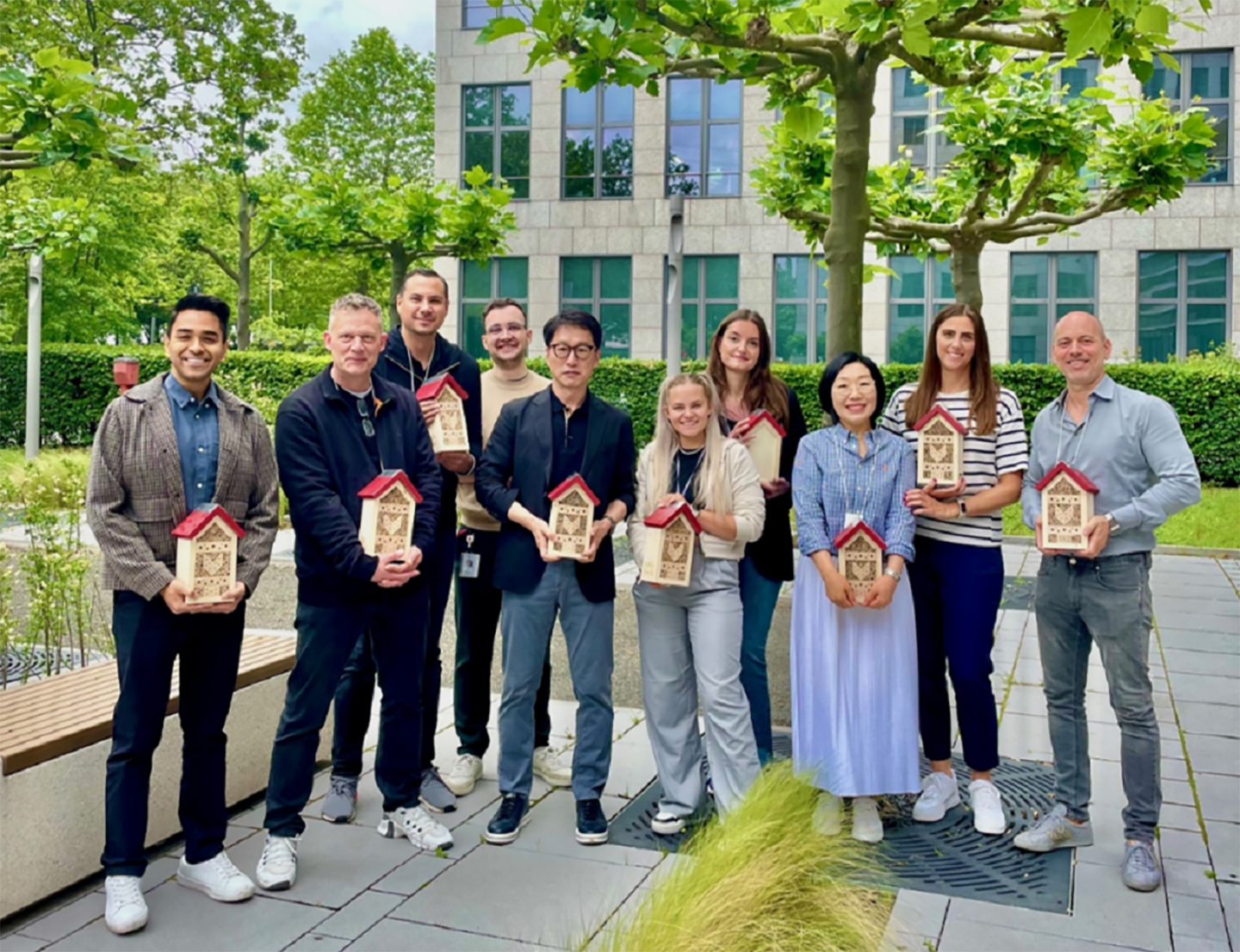 a photo of several smiling people holding insect hotel on their hand 