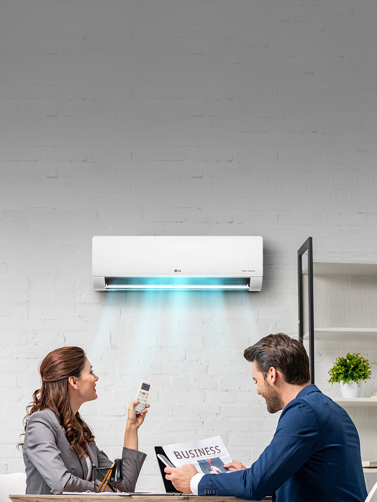 Couple enjoying LG split air conditioner cooling a modern room with remote saving energy bills.
