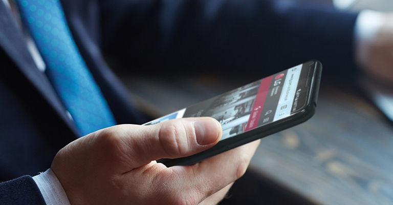 A man in a suit holds a smartphone in his right hand, displaying the LG website.