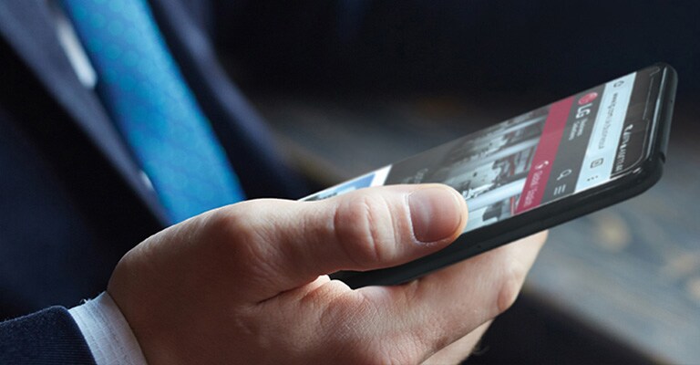  An image of a man holding a smartphone with LG web page on the screen.