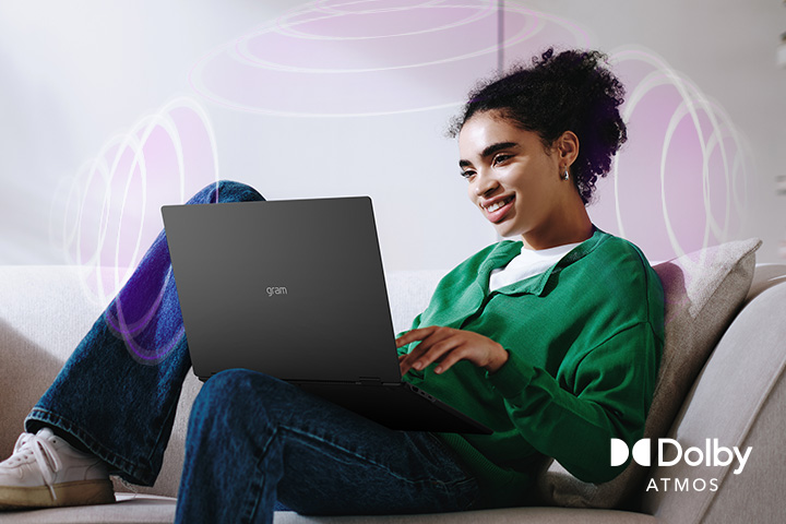 A person sitting on a couch, enjoying immersive audio while using an LG gram laptop. The text highlights Dolby Atmos technology, emphasizing a rich, expansive, 360-degree auditory experience. Surrounding sound waves in the background visually represent the immersive soundscape.