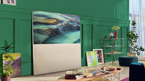 EASEL in Full View Mode leaning against a green living room wall and surrounded by art. There’s a scene of sand dunes on-screen.