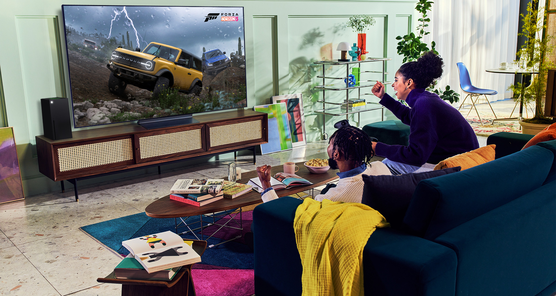 A person plays a racing game with an XBOX Series X controller on an LG OLED television